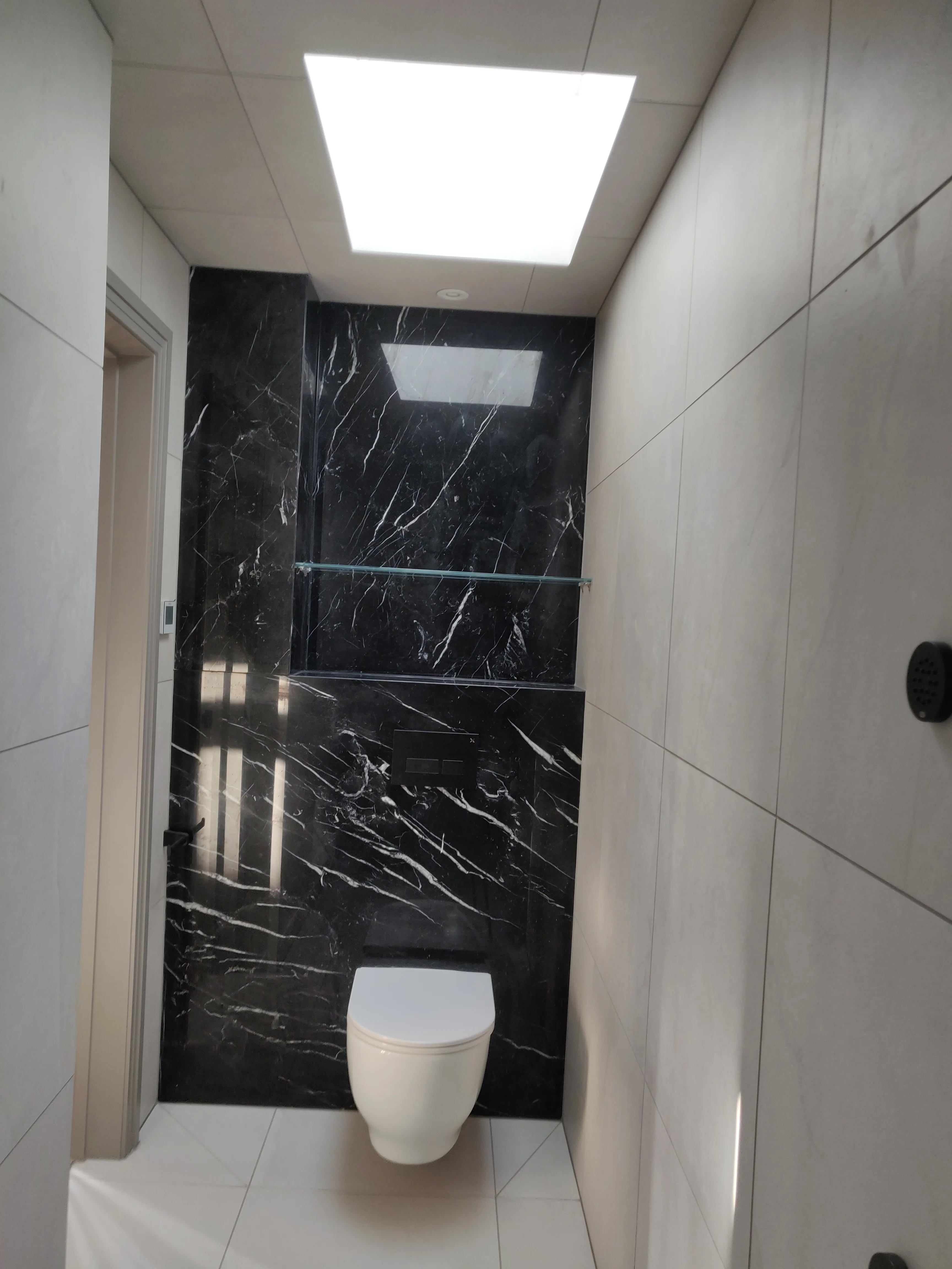 Modern bathroom installation with elegant black marble tiles and a skylight