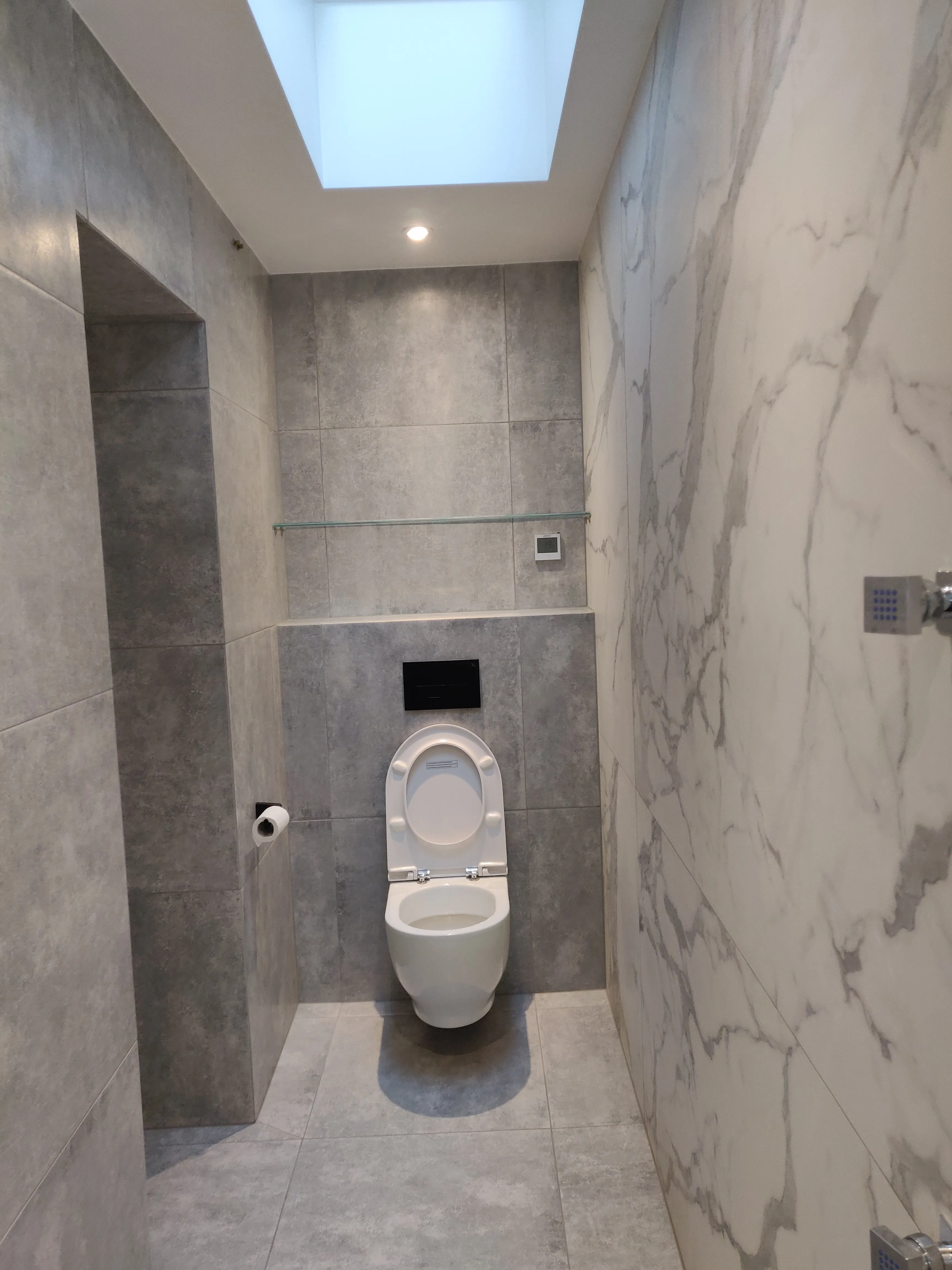 Modern bathroom refurbishment featuring grey tiles and skylight
