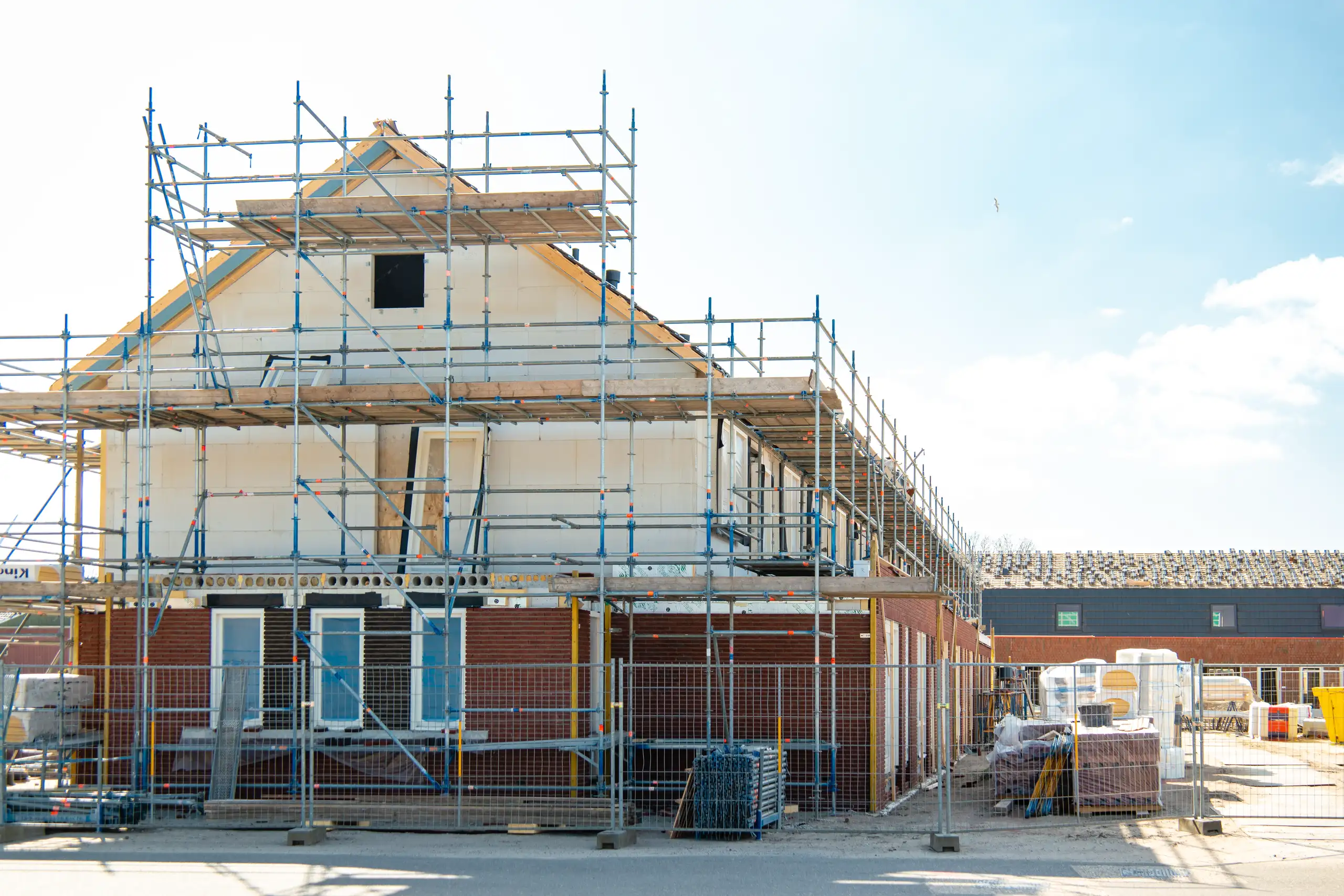 House extension project under construction with scaffolding and building materials visible