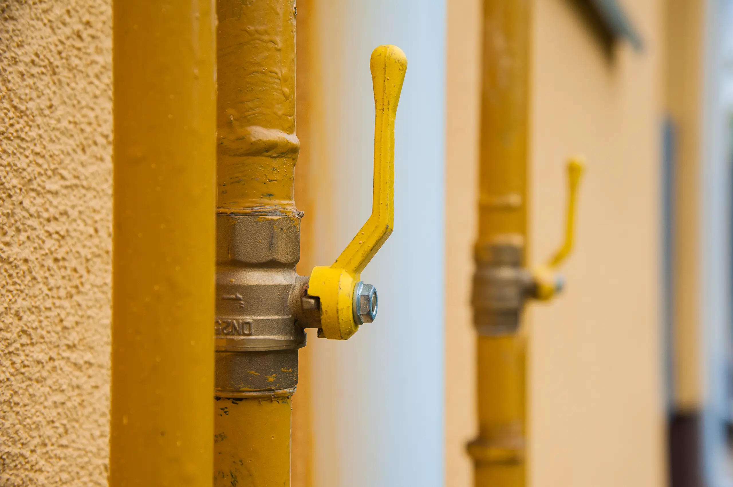 Close-up of yellow gas valves mounted on a wall, highlighting plumbing installation services