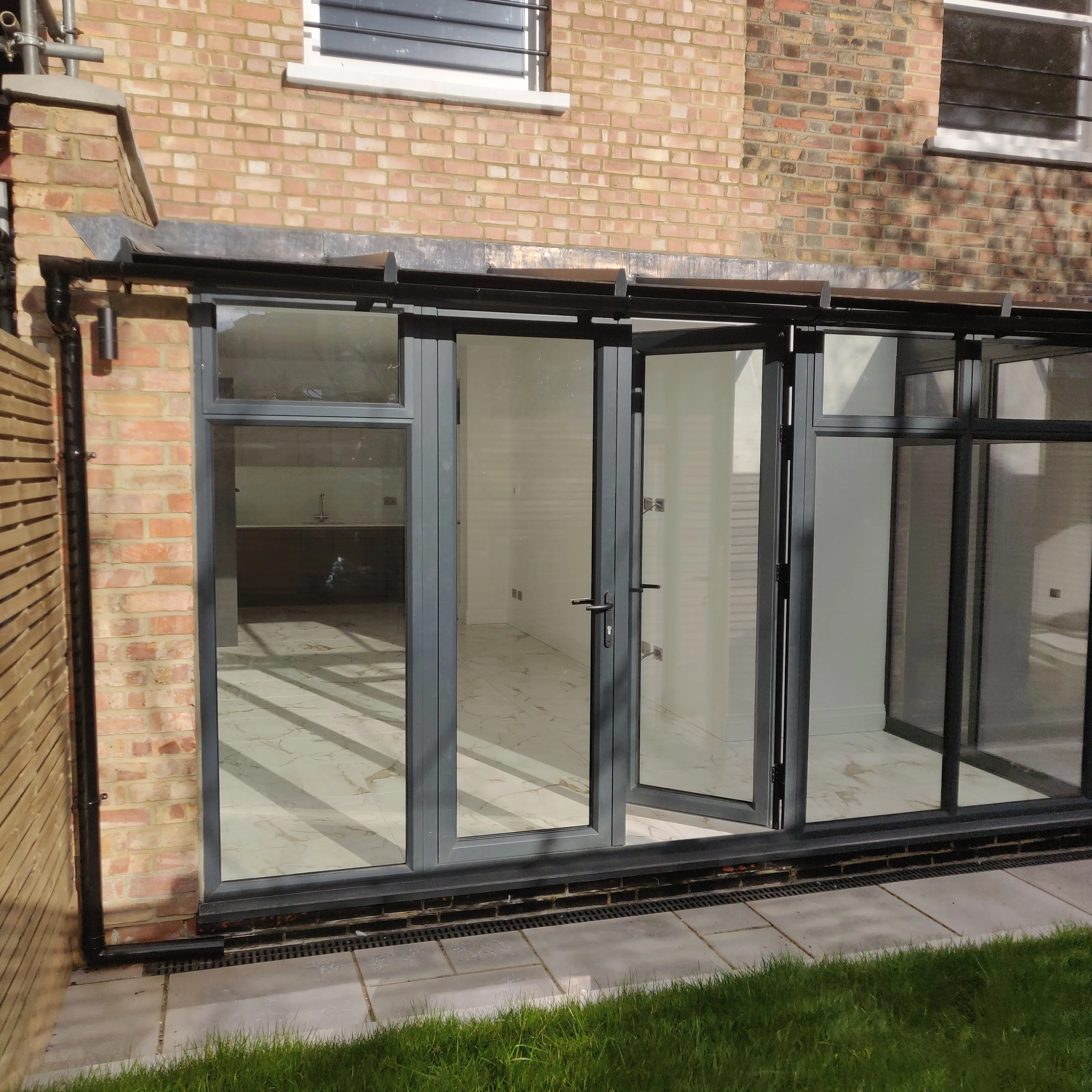 Modern glass extension with bi-fold doors, featuring an empty interior space