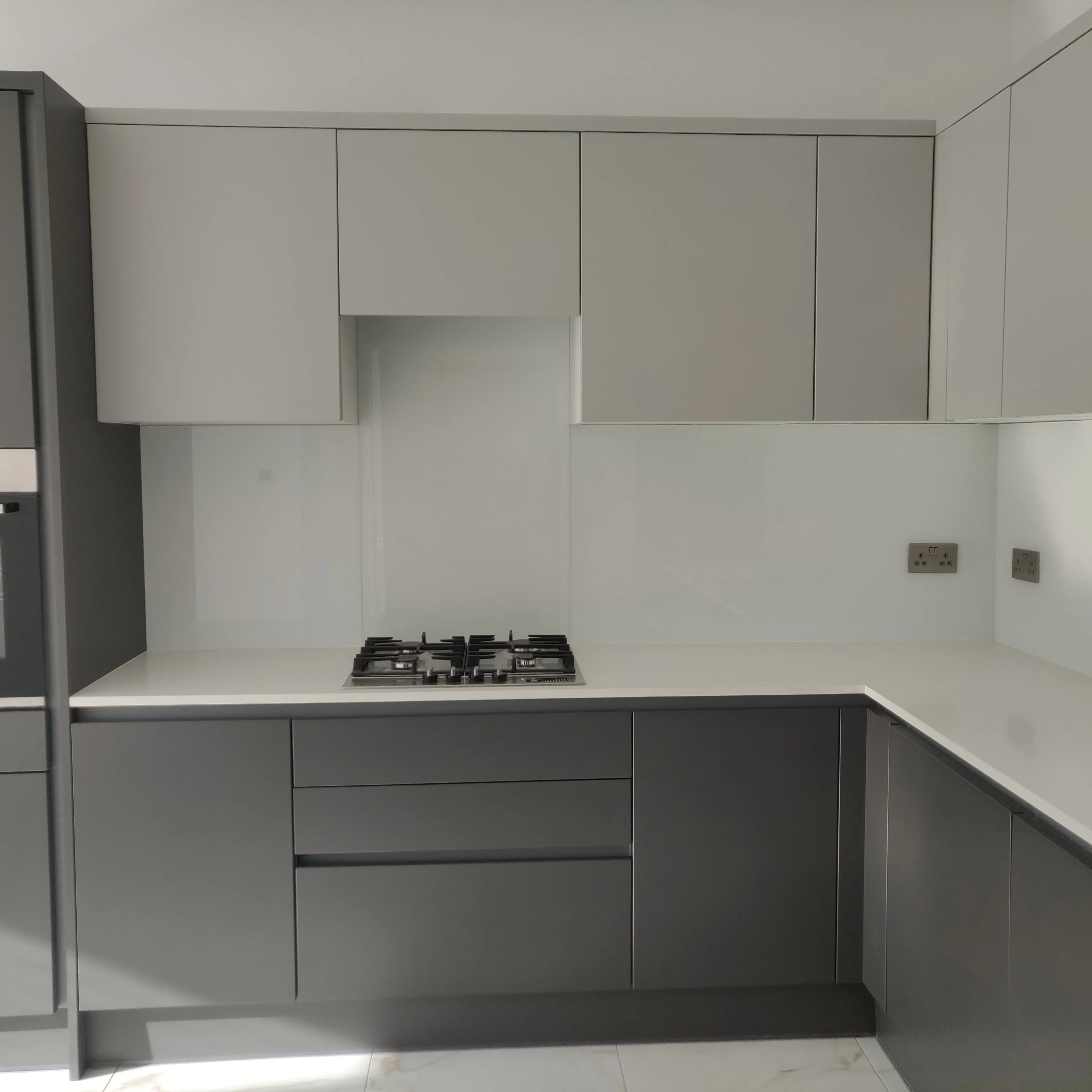 Modern kitchen refurbishment with sleek grey cabinetry and white countertops