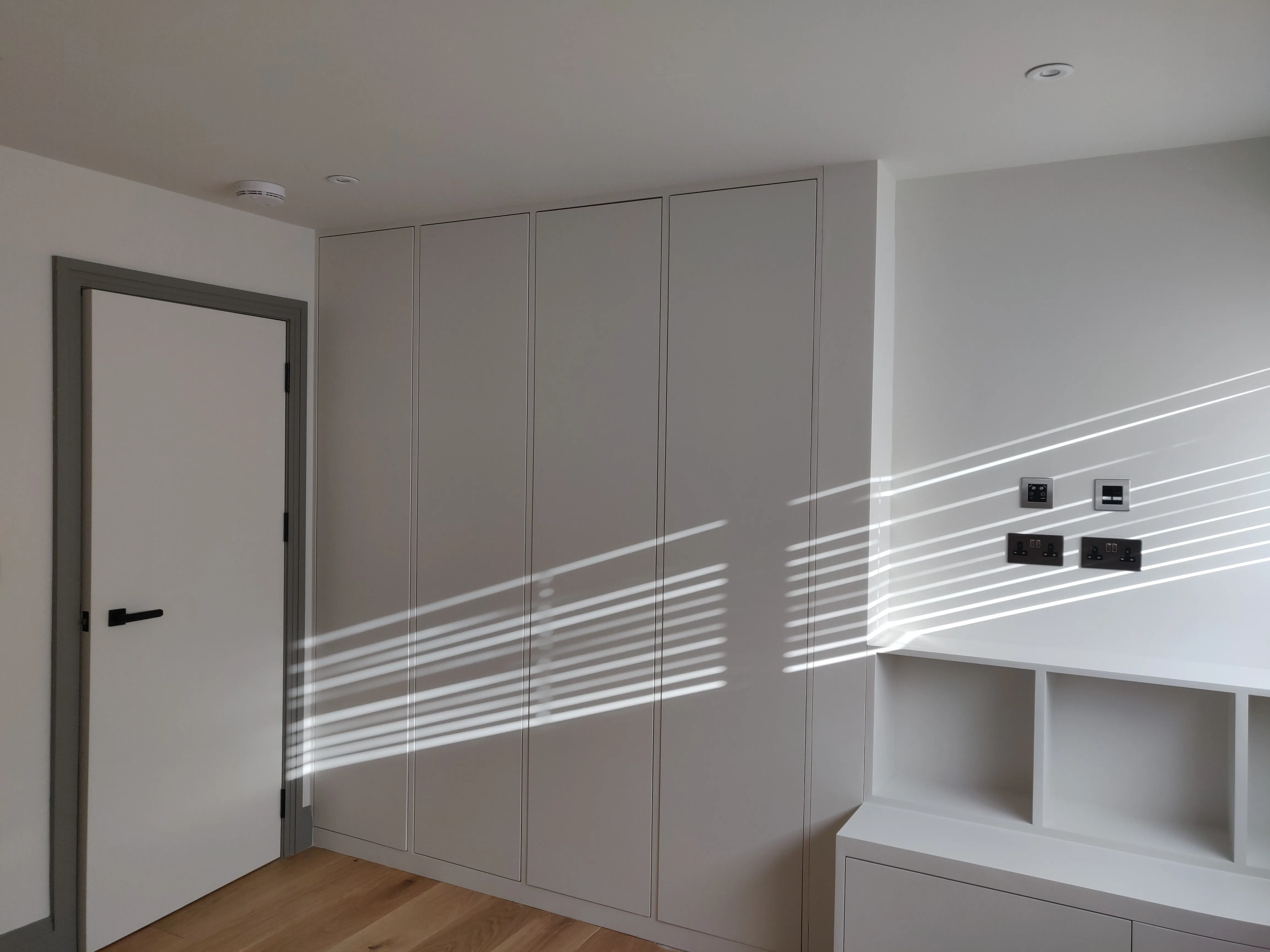 Modern interior with built-in wardrobe and light patterns on the wall, showcasing home refurbishment