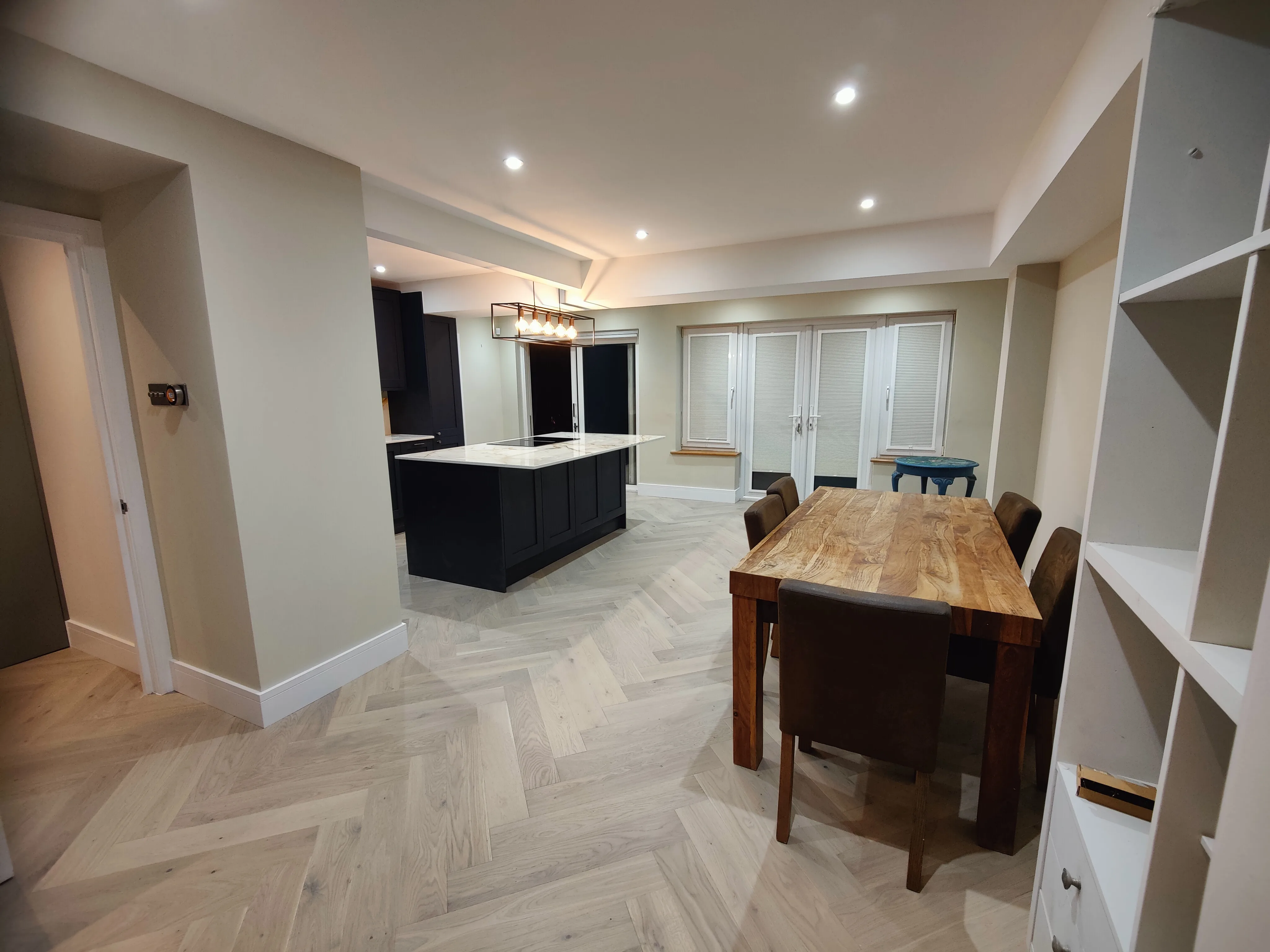 Modern kitchen refurbishment featuring a dining area with wooden table and stylish cabinets