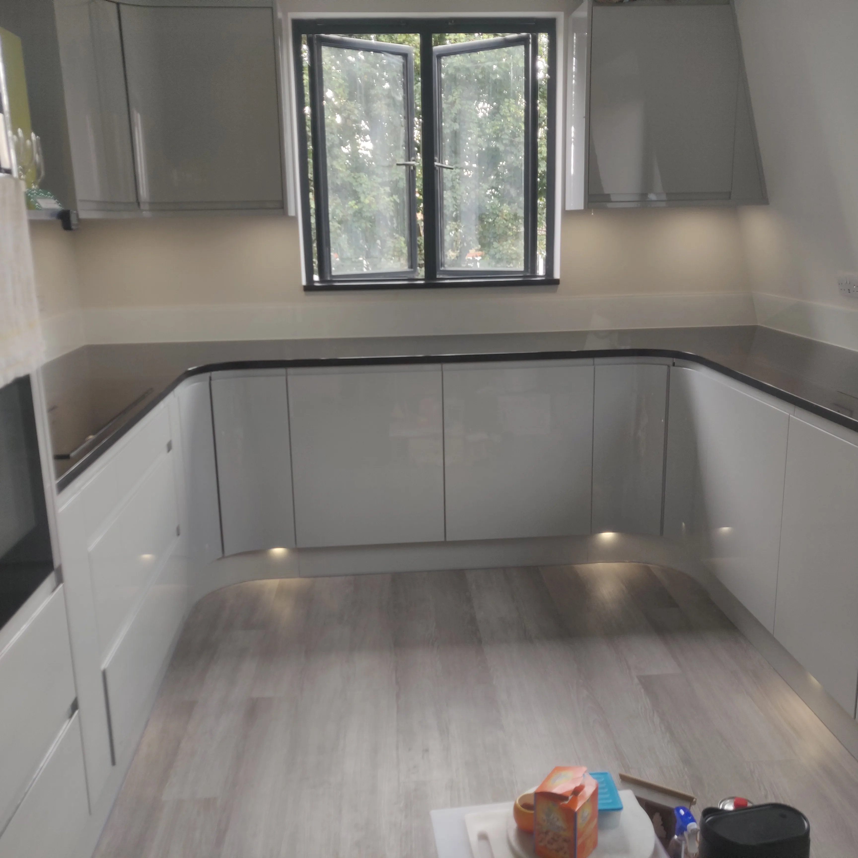 Modern kitchen refurbishment with high-gloss cabinetry and wood flooring