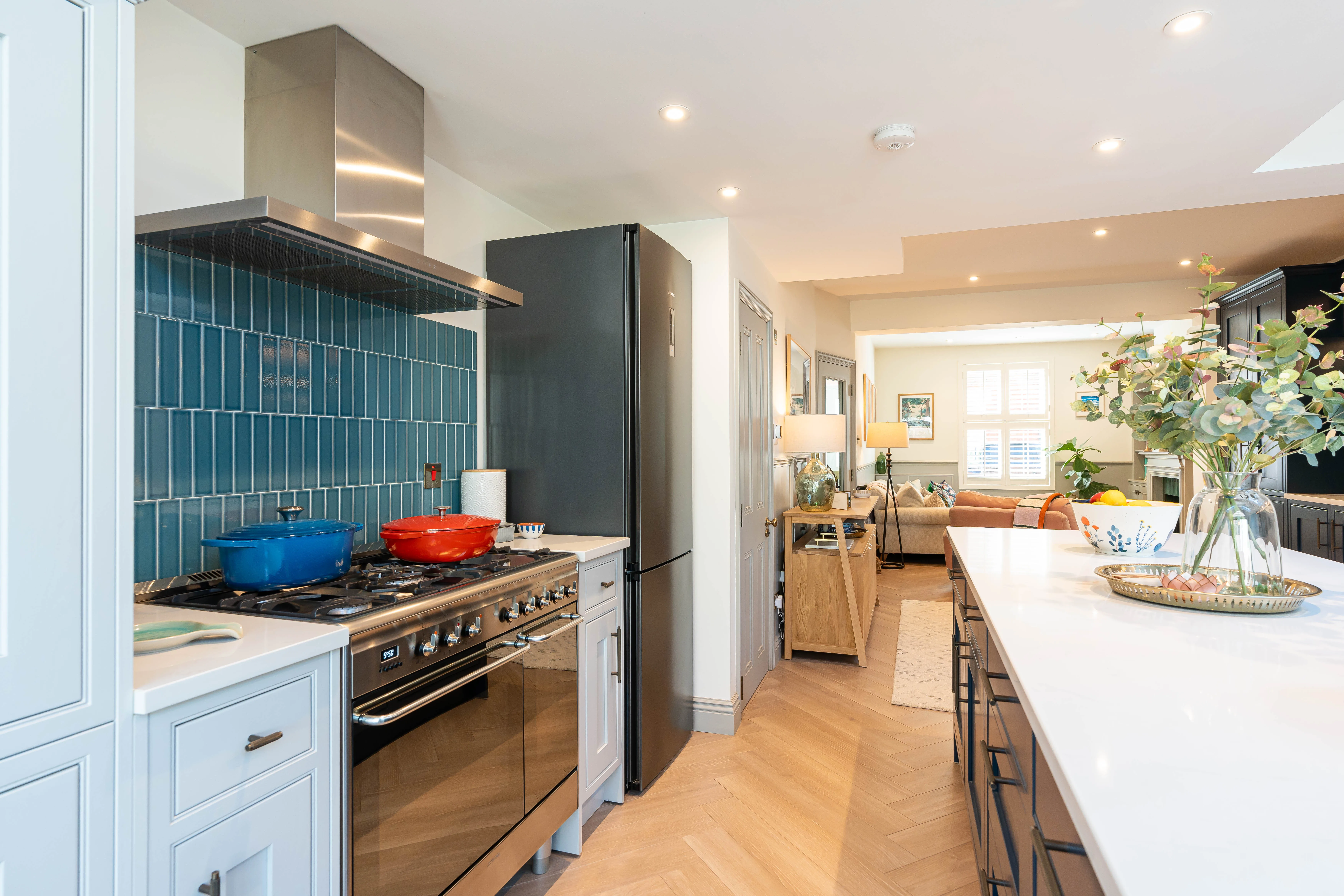 Modern kitchen refurbishment featuring a sleek design with blue tiles, stainless steel appliances, and wooden flooring