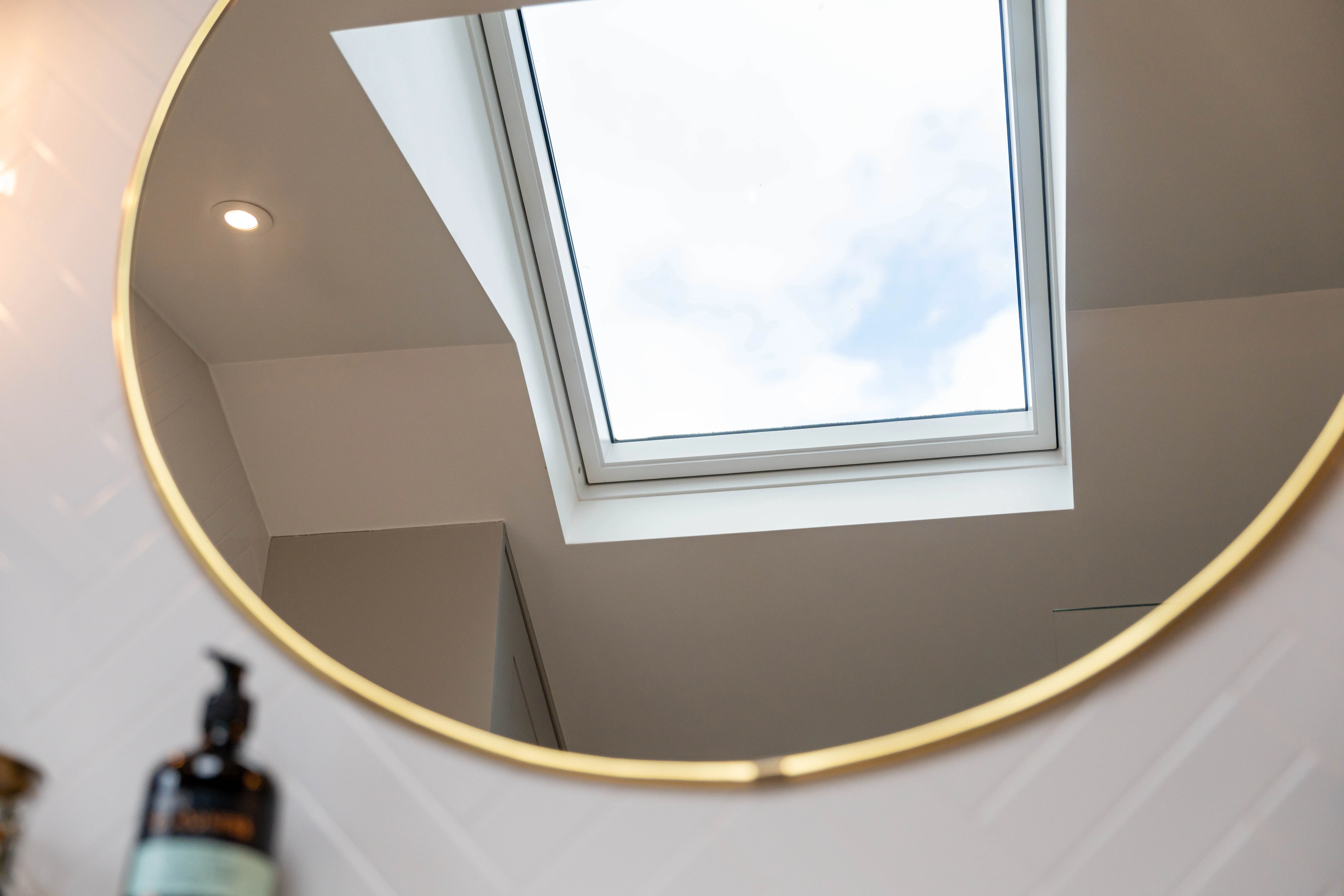 Skylight reflected in a round mirror, showcasing modern bathroom design